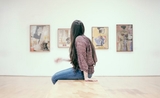 une fille assise observe les tableaux d'une exposition_0