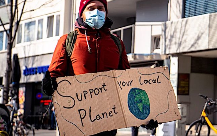 Une écologiste avec une pancarte support your local planet