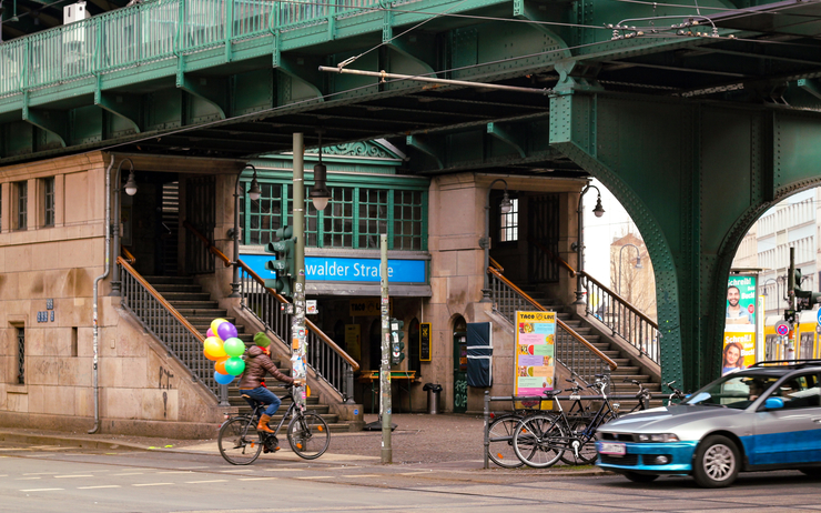Le pont de la station de métro Eberswalder strasse avec un cycliste transportant des ballons colorés