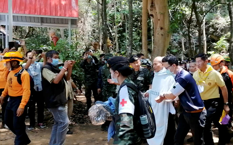 Le moine secouru de la grotte entoure par les secouristes et les officiels thailandais