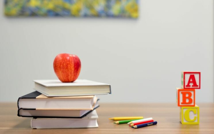 Une pomme est posée sur trois manuels scolaires