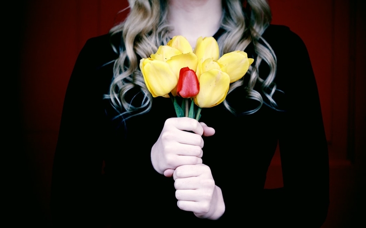 Une femme en tenue de deuil, un bouquet de fleurs à la main