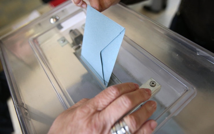 une personne dépose son bulletin de vote dans l'urne 