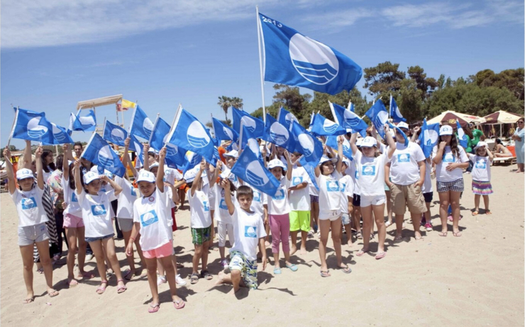 Des enfants tiennent des drapeaux bleus sur une plage en Andalousie
