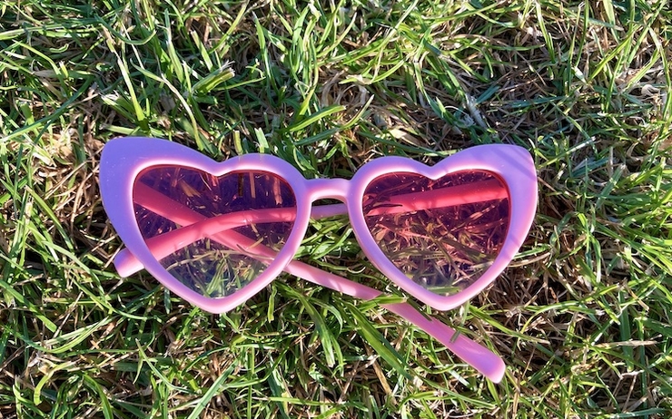 Des lunettes roses en forme de cœur posées dans le gazon