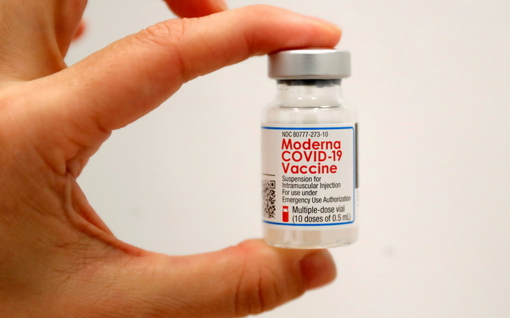 Une personne tient dans sa main une dose du vaccin Moderna
