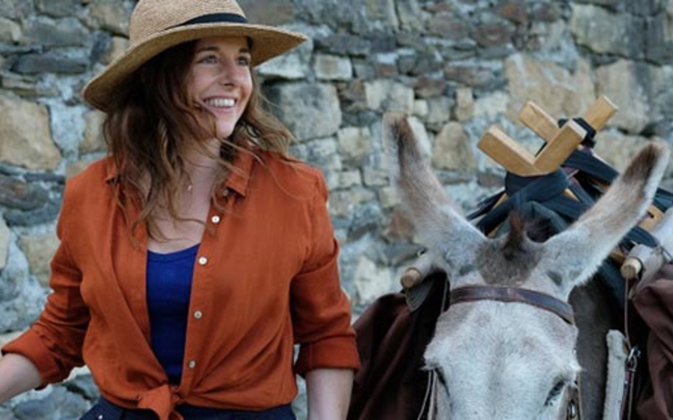 Une femme au chapeau de cowboy à côté d'un âne