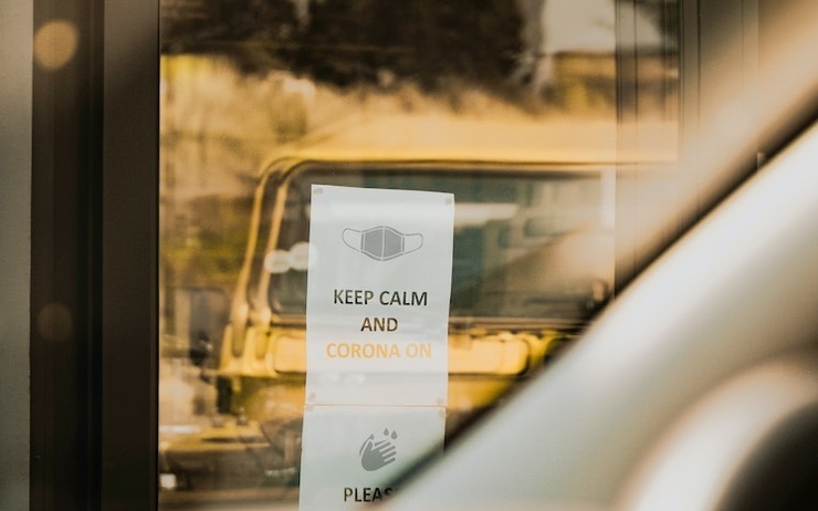 Une vitre avec une affiche où il est écrit  "Keep calm and Corona on"