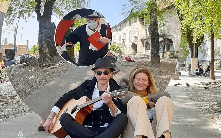 Deux artistes posent avec une guitare assis dans la rue
