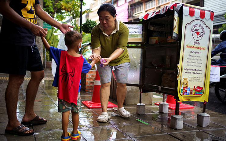 Un père et son enfant affectés par les mesures anti-covid reçoivent de la nourriture gratuite à Bangkok