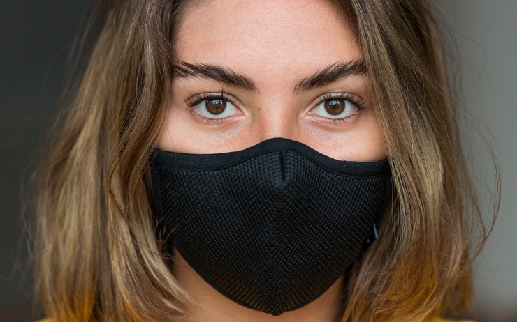 une jeune femme au regard vide porte un masque noir 