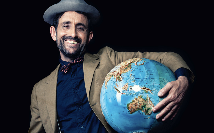 Un homme avec un chapeau qui tient un globe terrestre dans ses bras