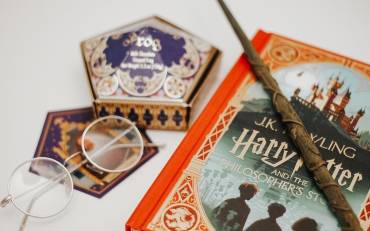 Les livres de la saga Harry Potter et une baguette trônent sur une table 