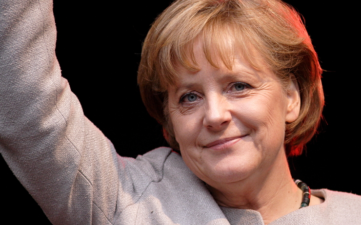 Angela Merkel lève le bras en souriant 