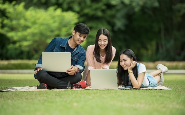Jeunes asiatiques sur consultant un ordinateur sur une pelouse 