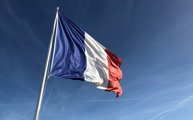 Un drapeau français avec un ciel clair en fond.