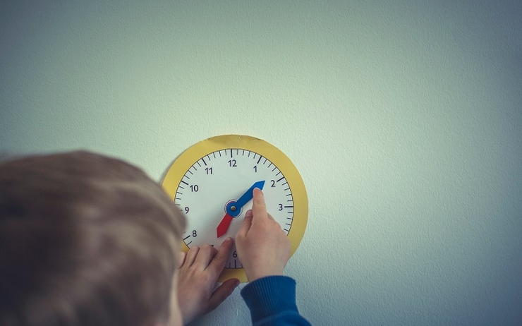 Un écolier réglant une horloge colorée pour enfants
