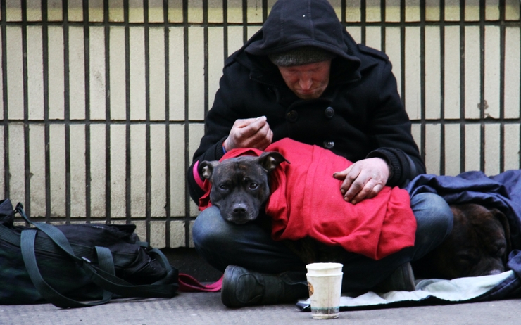 Un homme est assis dans la rue avec un chien sur ses genoux 