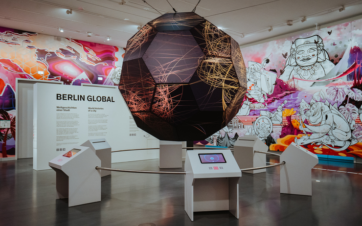 Un planisphère dans la première salle de l'exposition Global Berlin, avec un fresque un fond.
