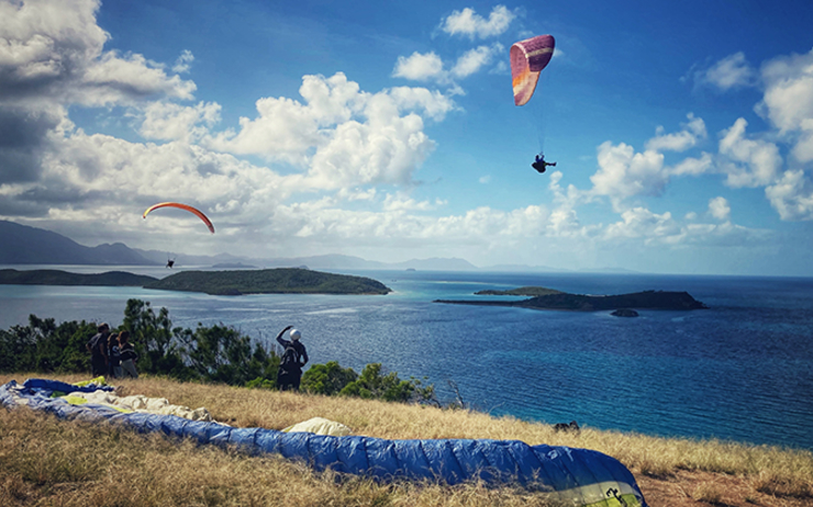 Trois personnes sautent en parapente du haut de la colline du Parc de Ouen Toro à Nouméa en Nouvelle-Calédonie 