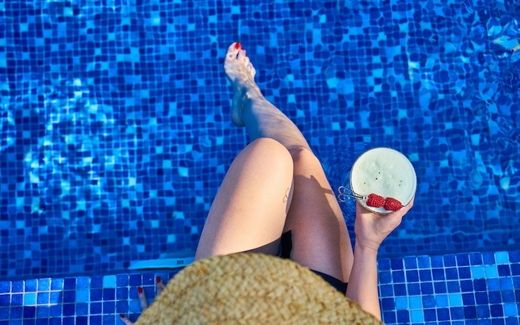 Une femme les pieds dans l'eau d'une piscine bleue