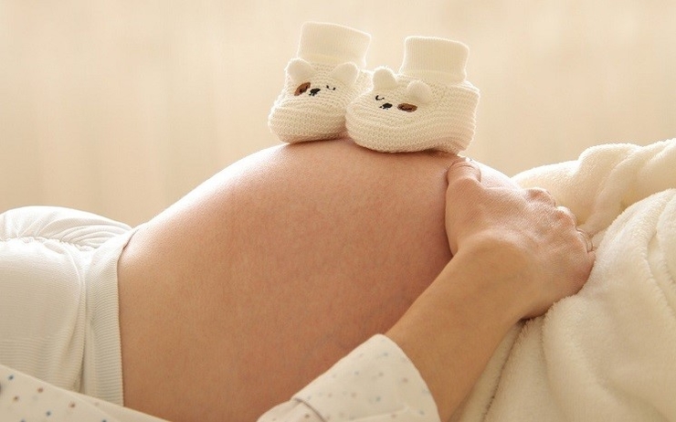ventre de femme enceinte avec chaussons de bébé