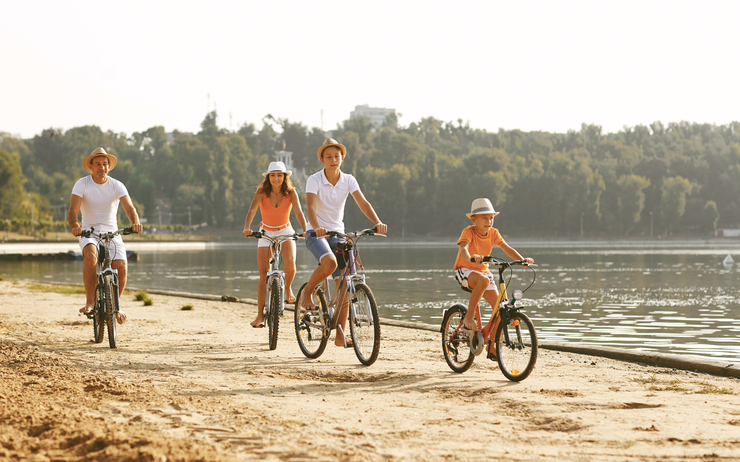 famille qui fait du vélo au bord d'un lac en vacance