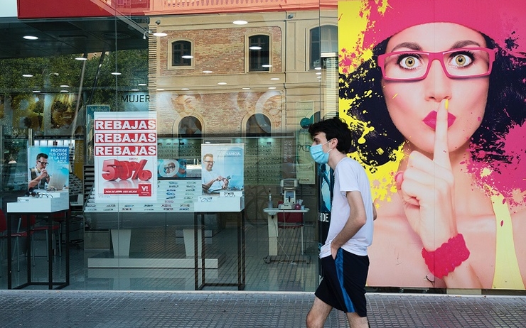 une personne passe devant la vitrine d'un magasin, en Espagne