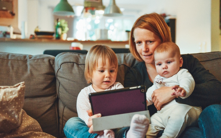 femme avec ses enfants entrain de regarder une tablette electronique