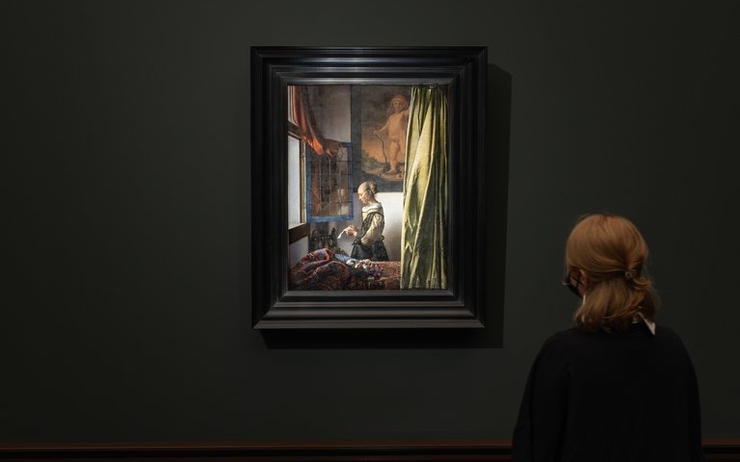 Une personne devant le tableau La Liseuse à la fenêtre de Vermeer dans l'exposition à la Gemaldegalerie de Dresde