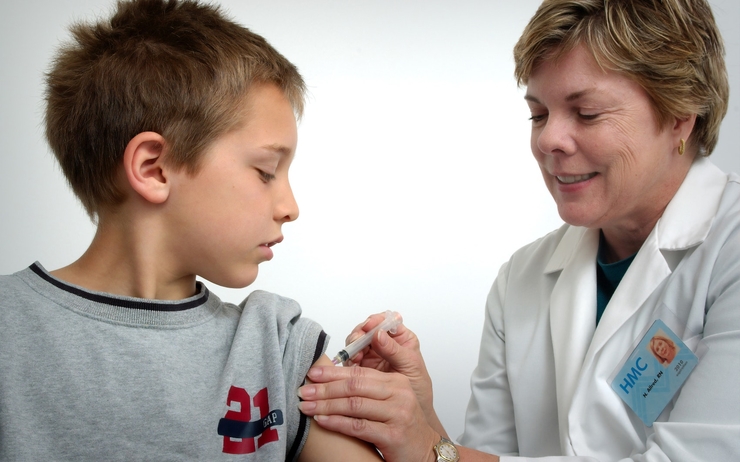 jeune garçon en train de se faire vacciner par une médecin 