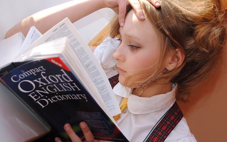 Une fille lisant attentivement le dictionnaire Oxford en anglais