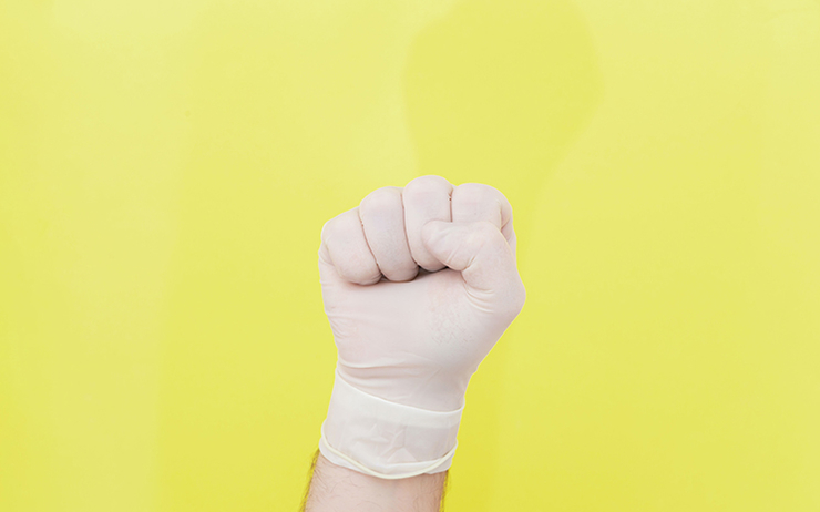 le poing levé avec un gant chirurgical sur fond jaune 