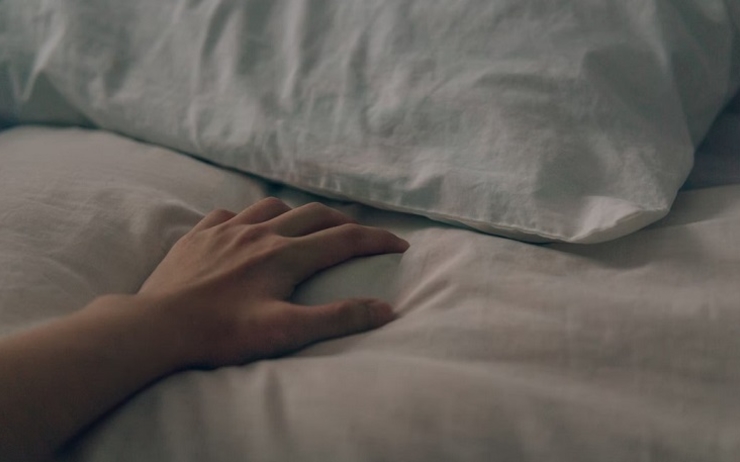 une main de femme étendue sur un lit
