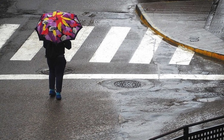 Une personne en train de marcher sous la pluie avec un parapluie