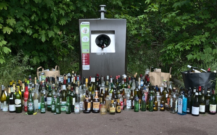 De nombreuses bouteilles d'alcool entassées autour d'une poubelle