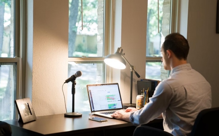 un homme en chemise blanche travaille avec son ordinateur portable en télétravail