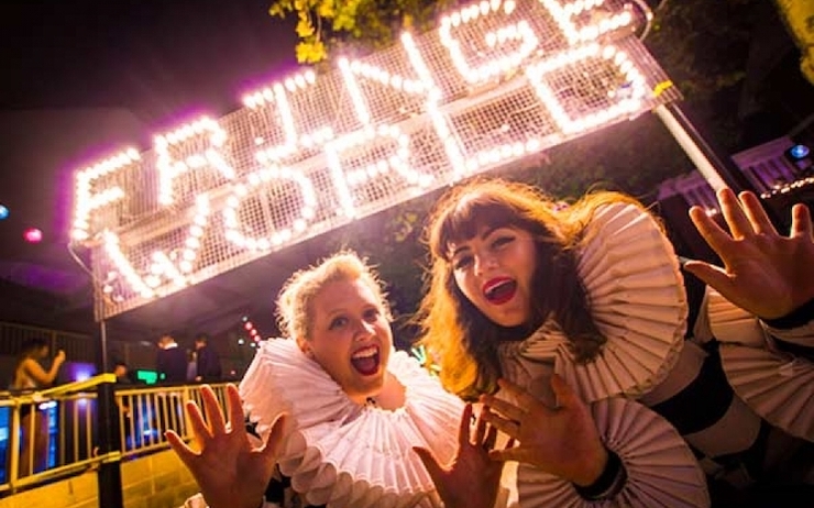 Deux femmes devant l'inscription lumineuse "Fringe World"