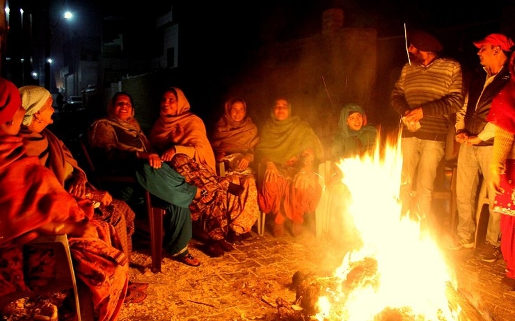 Personnes réunies autour d'un feu pour Lohri en Inde du nord