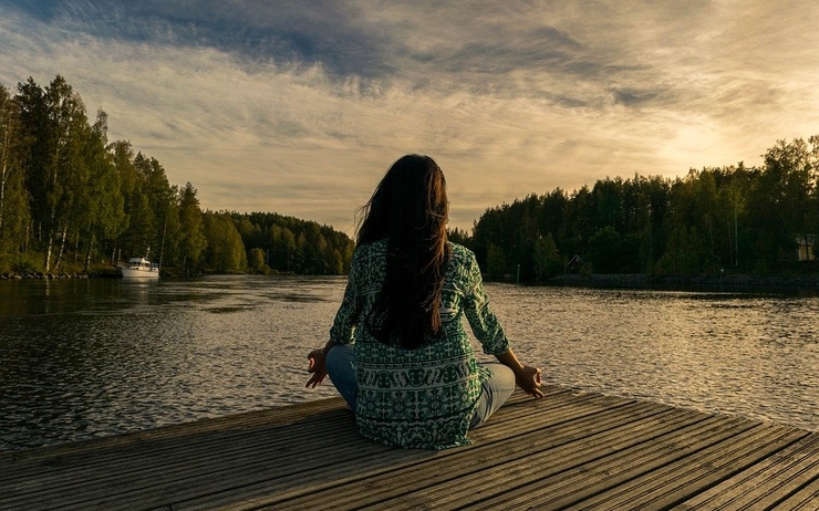 une femme qui fait du yoga devant un lac