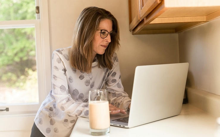 une femme consulte son ordinateur, dans son logement, en Espagne