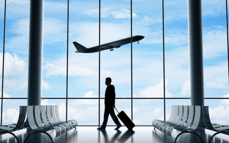 Un homme marchant dans un aéroport tandis qu'un avion prend son envol