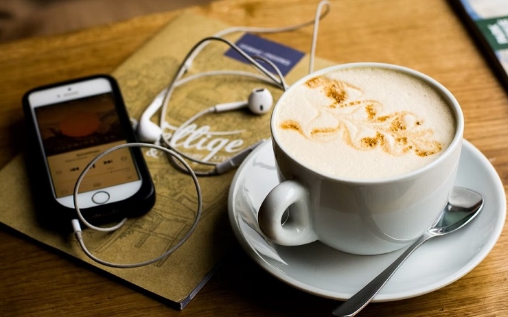 smartphone branché à des écouteurs avec un cappuccino
