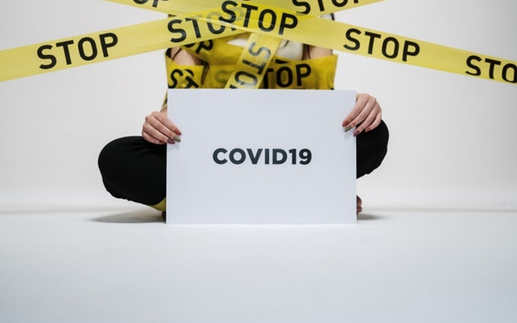 Une personne tenant une pancarte "covid-19" et recouverte de rubalise
