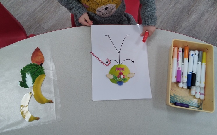 Un enfant devant sa récréation d'un dessin de bonhomme baton à la manière d'Arcimboldo dans le cadre des activités bilingues organisées à la Little Agnes Nursery par Véronique Aufrand