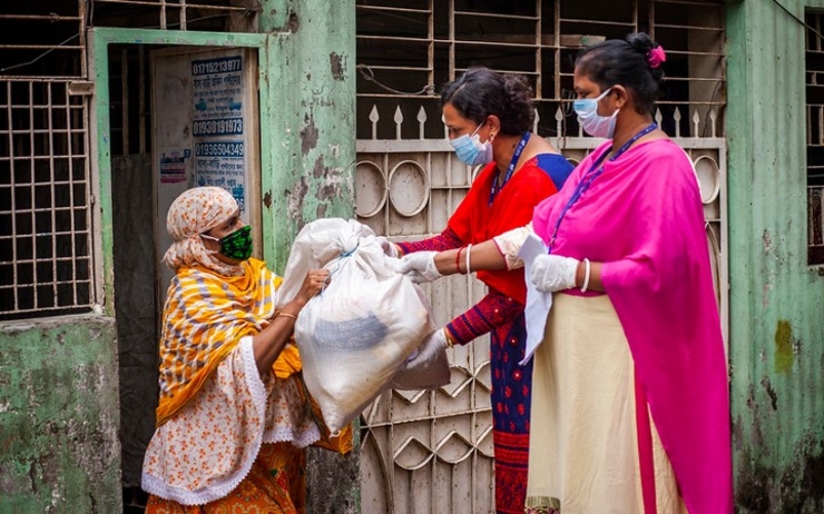Femmes masquées distribuant des rations alimentaires
