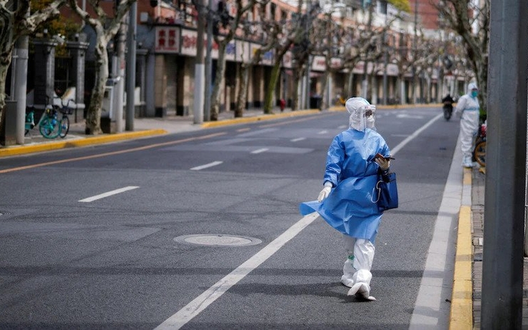 une femme marche dans la rue de Shanghai en combinaison contre le covid