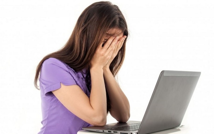 jeune femme se tient la tête devant son ordinateur portable