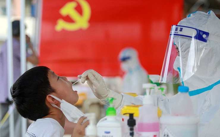 une personne en blouse test un enfant pour le covid en Chine 