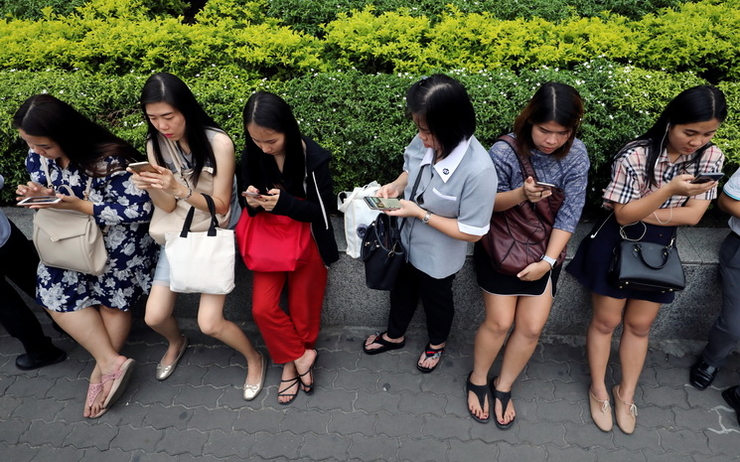 Des jeunes filles regardent leur téléphone dans la rue 